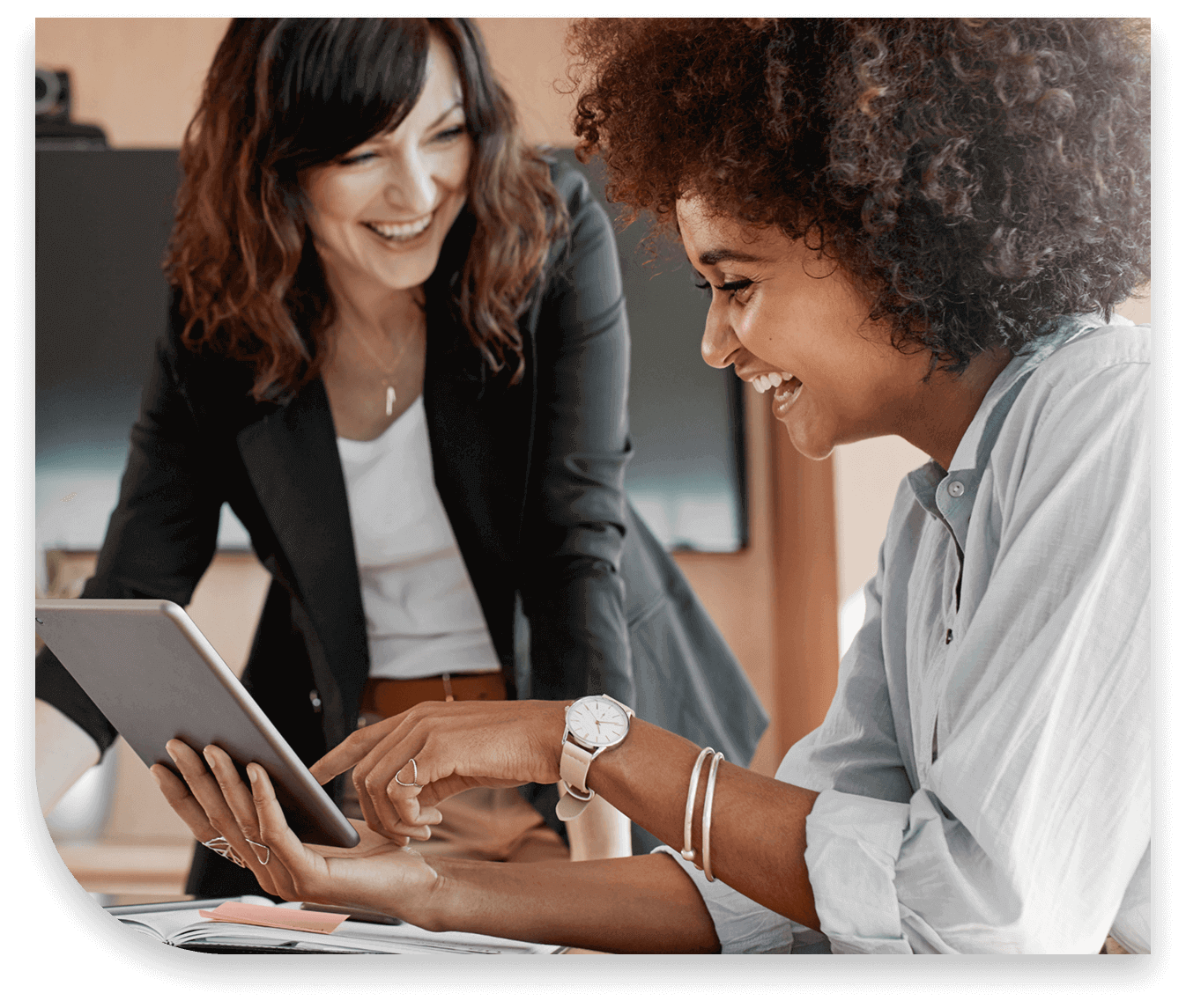 Two Syneos Health employees collaborating in the Graduate Training Program, reviewing information on a tablet in an office.